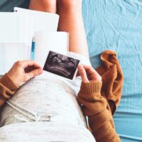 birth plan template. Pregnant woman looking at ultrasound image and writing birth plan