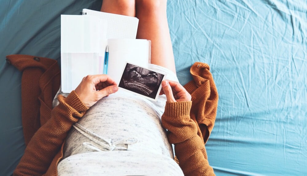 Pregnant woman looking at ultrasound image and writing birth plan