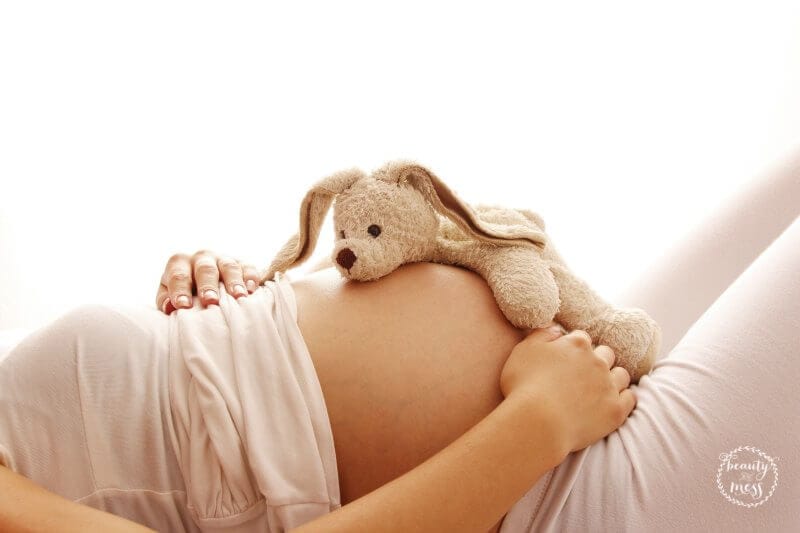 a pregnant woman with rabbit stuffie on belly- baby stuff