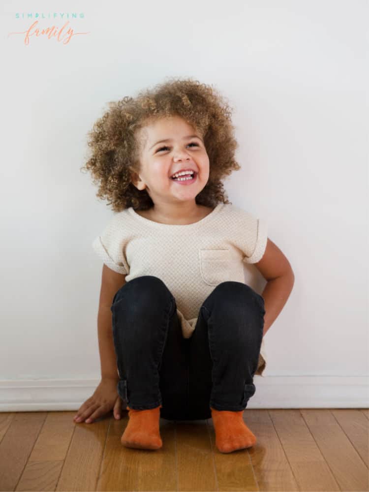 little girl with curly hair sitting on floor listening to podcasts for kids