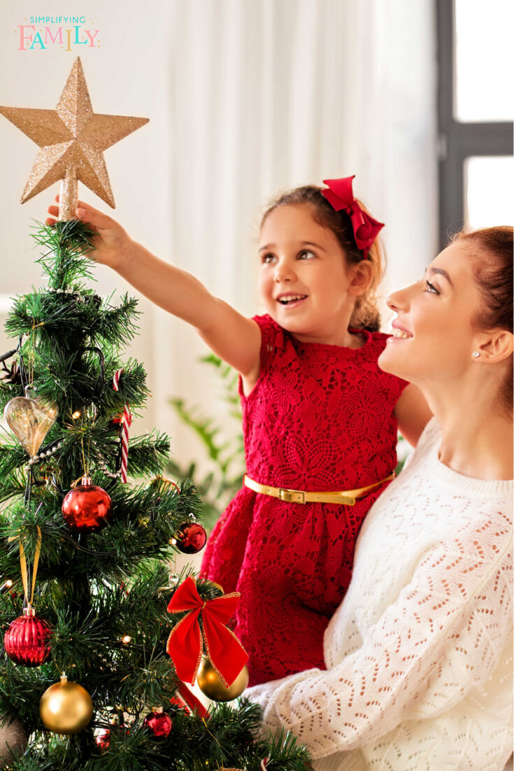 mom and daughter enjoying the holidays putting star on top of the decorated Christmas tree